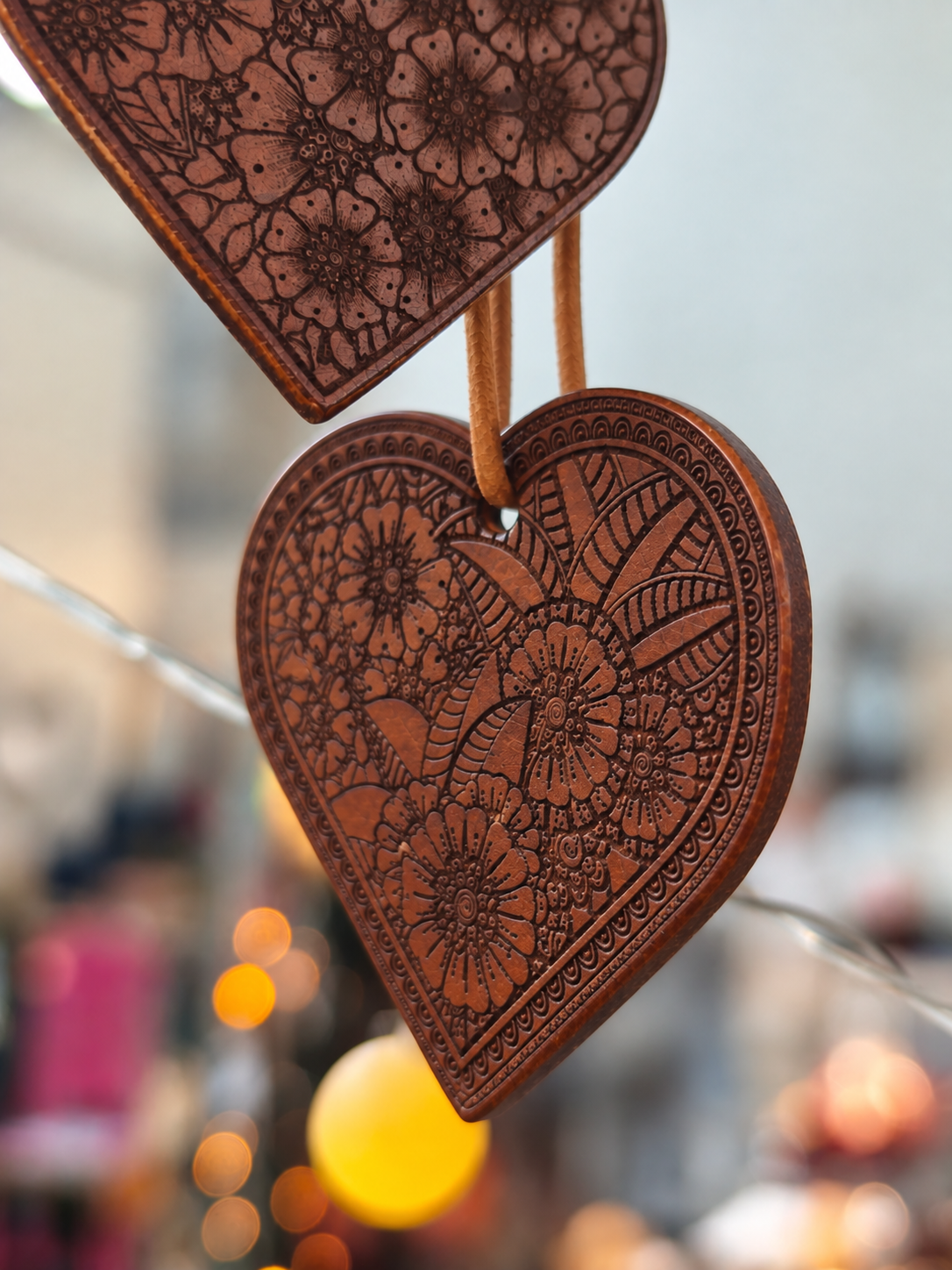 Floraler Herzanhänger aus Leder mit kunstvoller Gravur. Nahaufnahme der Ornamente
